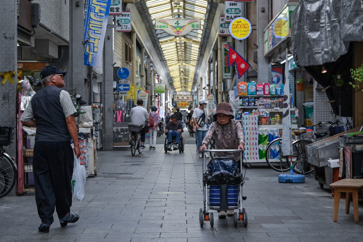 This photo taken on October 1, 2025 shows elderly shoppers walking through the Tsurumibashi &ldquo;shotengai&ldquo;, an old covered shopping street in the Nishinari ward of Osaka.