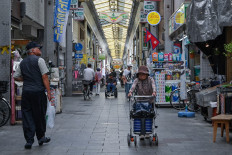 This photo taken on October 1, 2025 shows elderly shoppers walking through the Tsurumibashi &ldquo;shotengai&ldquo;, an old covered shopping street in the Nishinari ward of Osaka.