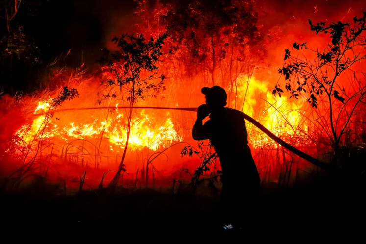 A firefighter from the Regional Disaster Management Agency douses a forest fire at Sungai Rambutan village in Ogan Ilir, South Sumatra on Sept. 11, 2026. Toxic haze has shrouded parts of Indonesia and Malaysia for weeks as Jakarta struggles to contain fires that have scorched large tracts of Borneo and Sumatra, with the smoke drifting into neighboring Malaysia, Singapore and Brunei. 