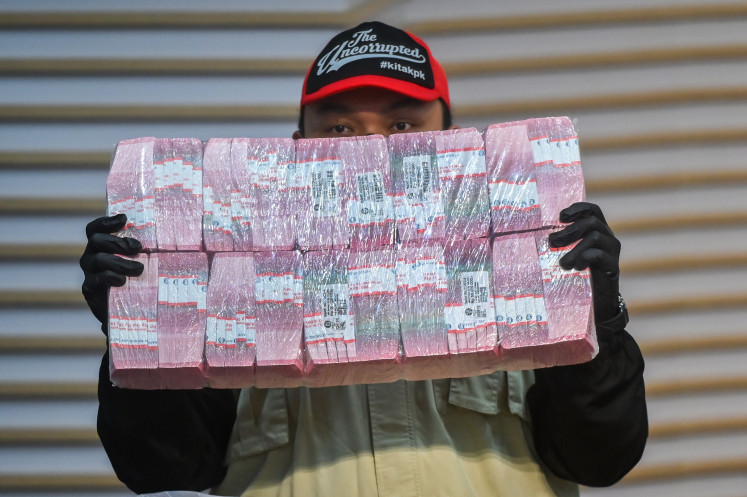 Corruption Eradication Commission (KPK) investigators hold up cash on Wednesday seized during the arrest of eight suspects in a bribery case involving the issuance of right-to-build (HGB) permits at the Agrarian and Spatial Planning Ministry. 
