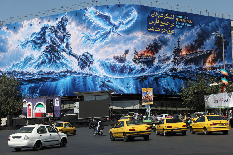 People drive past a billboard about the Strait of Hormuz, on a building in Tehran, Iran, on September 16, 2026.