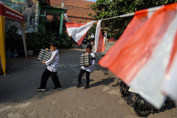 Students carry meal packages disbursed through the free nutritious meal program on Sept. 4 at SDN Jati Asih X state elementary school in Bekasi, West Java.