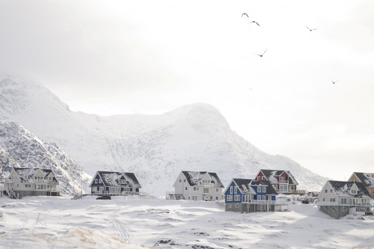 Birds fly over houses overshadowed by the mountain in Nuuk, Greenland, on March 10, 2026.