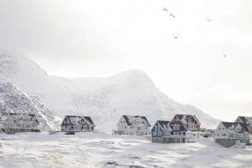 Birds fly over houses overshadowed by the mountain in Nuuk, Greenland, on March 10, 2026.