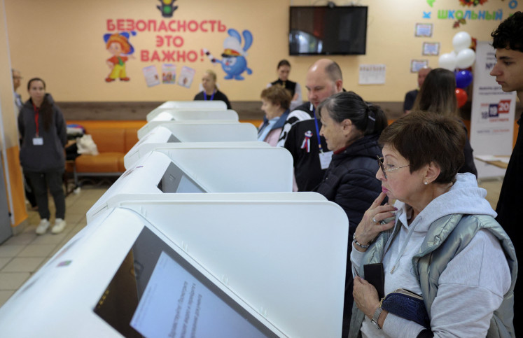 People stand in front of online voting machines at a polling station on the final day of Russia's three-day parliamentary election in Moscow, Russia, September 20, 2026.