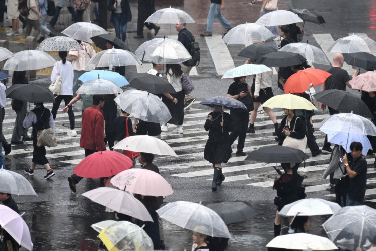 Pedestrians with umbrellas walk on a crossing as rain falls in Tokyo's Shibuya district on September 20, 2026.