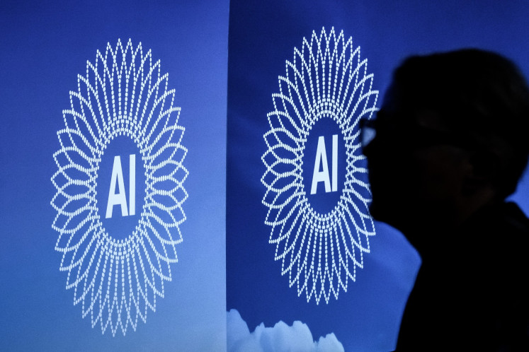A person is silhouetted next to the logo of the first Global Dialogue on AI Governance, in Geneva on July 6, 2026. UN secretary-general Guterres called for a global governance system to shape artificial intelligence for the good of humanity, warning against allowing the technology itself to &ldquo;vibe-code&ldquo; our future.