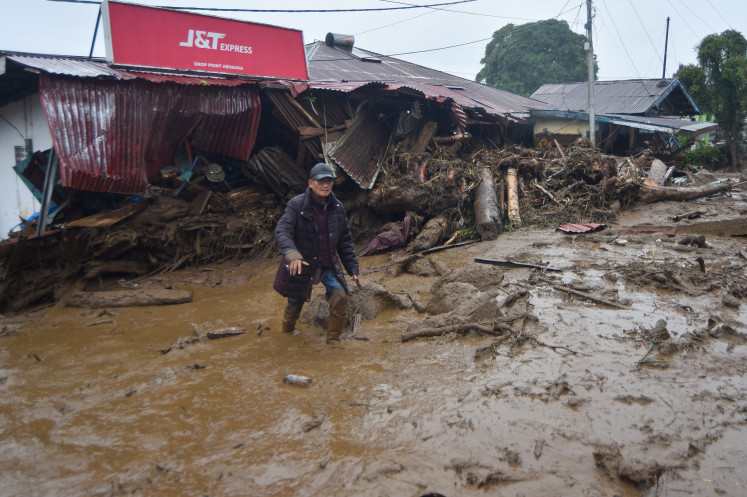 A resident walks past debris following a flash flood in, Solok regency, West Sumatra, on Sept 22, 2026. The flash flood, which struck a day prior, killed one, and injured four others.