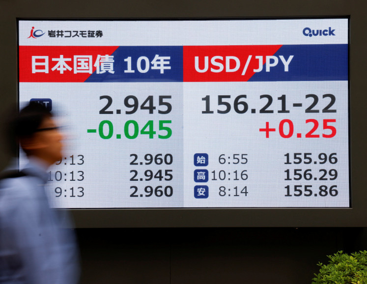 A pedestrian walks in front of a stock quotation board displaying the level of Japan's 10-year government bonds and the exchange rate between the US dollar and Japanese Yen, outside a brokerage in Tokyo, on Sept. 18, 2026.