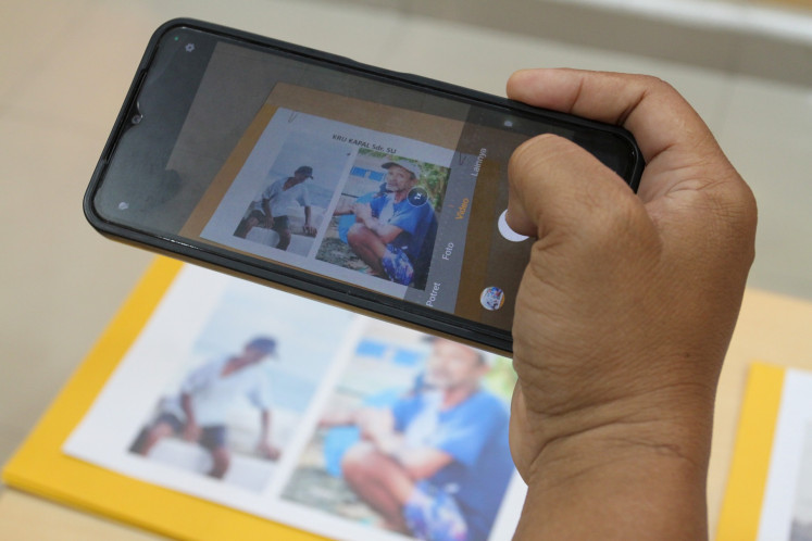 A journalist takes photo of a picture showing Surakman, a crewmember of the boat Arupadhatu 1 that went missing while carrying journalists covering the eruption of Mount Anak Krakatau in the Sunda Strait, during a press briefing on Sept. 23 at the Banten Police headquarters in Serang, Banten. The police identified a body found on Enggano Island, Bengkulu, as Surakman following DNA identification.