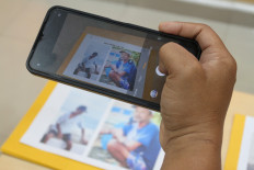 A journalist takes photo of a picture showing Surakman, a crewmember of the boat Arupadhatu 1 that went missing while carrying journalists covering the eruption of Mount Anak Krakatau in the Sunda Strait, during a press briefing on Sept. 23 at the Banten Police headquarters in Serang, Banten. The police identified a body found on Enggano Island, Bengkulu, as Surakman following DNA identification.
