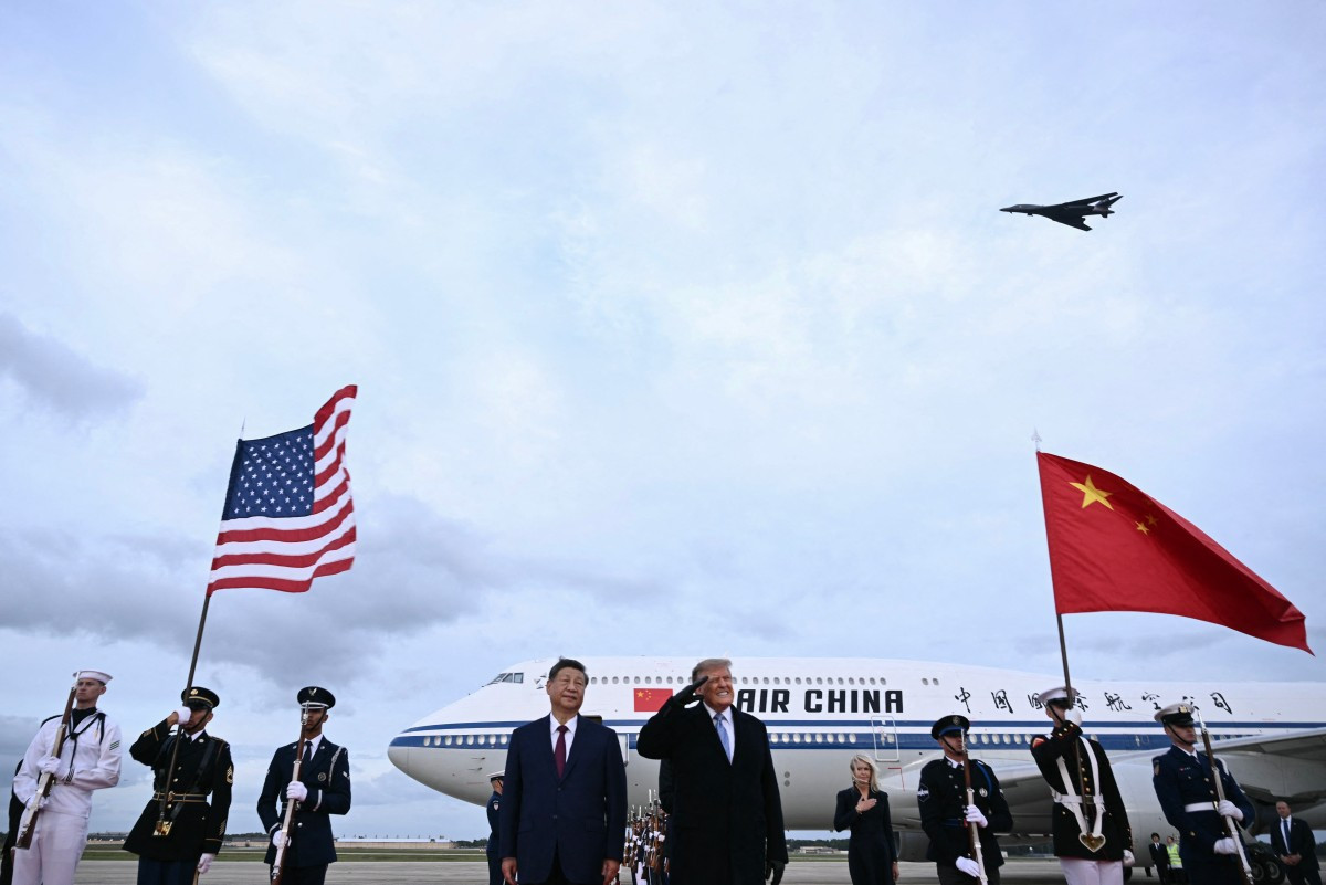 US President Donald Trump reacts after a B1 bomber flew past during the national anthems while he greeted Chinese President Xi Jinping upon his arrival at Joint Base Andrews in Maryland on September 23, 2026.