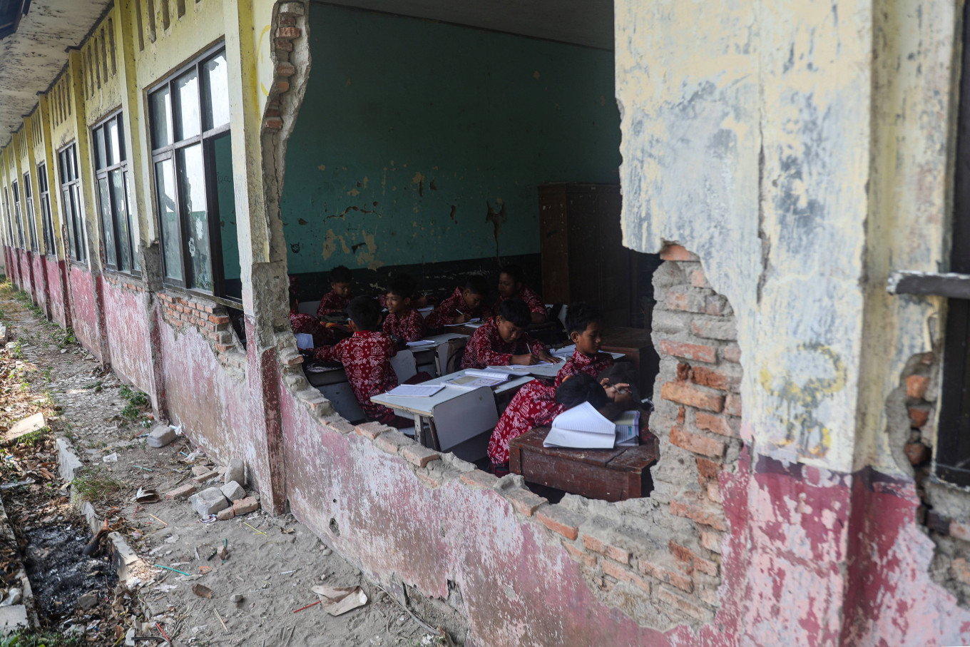 Students attend a class on Sept. 23 beside a collapsed wall at SDN 3 Sukajadi
elementary school in Sukakarya, Bekasi regency, West Java. According to the
school, three classrooms have been damaged for the past three years because of
the aging building, disrupting lessons and posing safety risks to students.