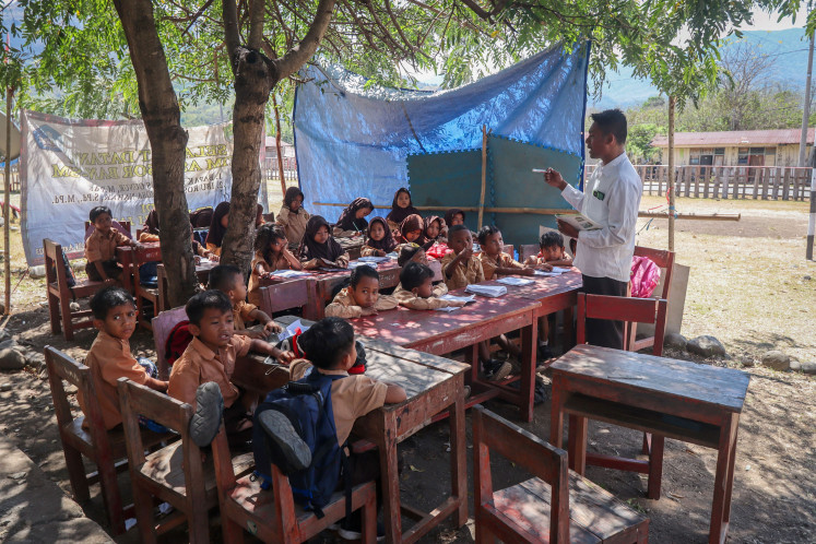 A teacher gives a lesson to students on Sept. 9 under a tree at SDN Jarak elementary school in Golo Mori village, West Manggarai, East Nusa Tenggara (NTT), after damage to their classroom forced lessons outdoors. Elementary and Secondary Education Ministry data show that 1,931 schools, involving 171,476 students, have resumed classes after being temporarily closed following the NTT earthquake.