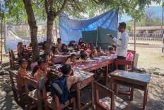 A teacher gives a lesson to students on Sept. 9 under a tree at SDN Jarak elementary school in Golo Mori village, West Manggarai, East Nusa Tenggara (NTT), after damage to their classroom forced lessons outdoors. Elementary and Secondary Education Ministry data show that 1,931 schools, involving 171,476 students, have resumed classes after being temporarily closed following the NTT earthquake.