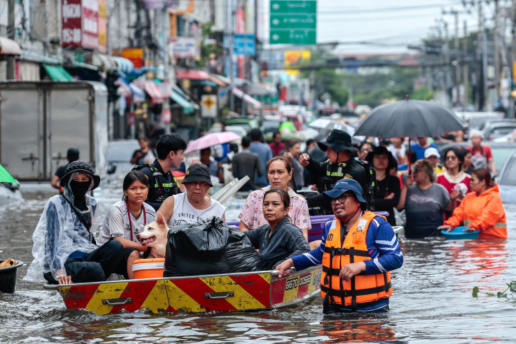 People are transported by boats as others wade through a flooded area during heavy rain in Bangkok, Thailand, September 27, 2026.