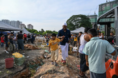 A Rohingya refugee living in Malaysia holds his son while others prepare to slaughter cows during the Idul Adha festival in Kuala Lumpur on July 10, 2022. 