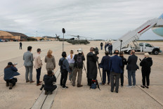 A reporter from Real America's Voice News, after the White House has blocked CNN from traveling with President Donald Trump on Air Force One for a trip on Saturday to Tennessee, and other media members stand next to Air Force One with a US military transport helicopter seen in the background at Joint Base Andrews, Maryland, US, September 26, 2026.