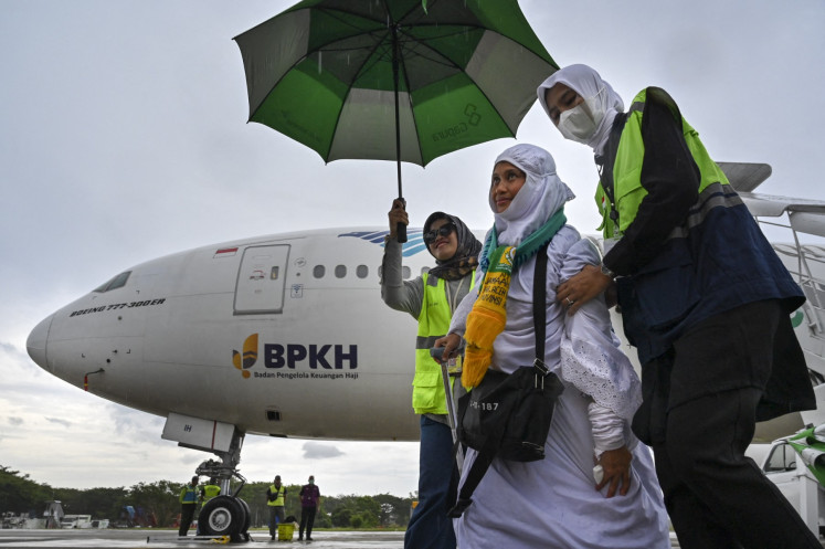 Members of ground staff escort a woman upon her arrival at Sultan Iskandar Muda International Airport in Blang Bintang, Aceh on July 10, 2024, after performing the annual haj.