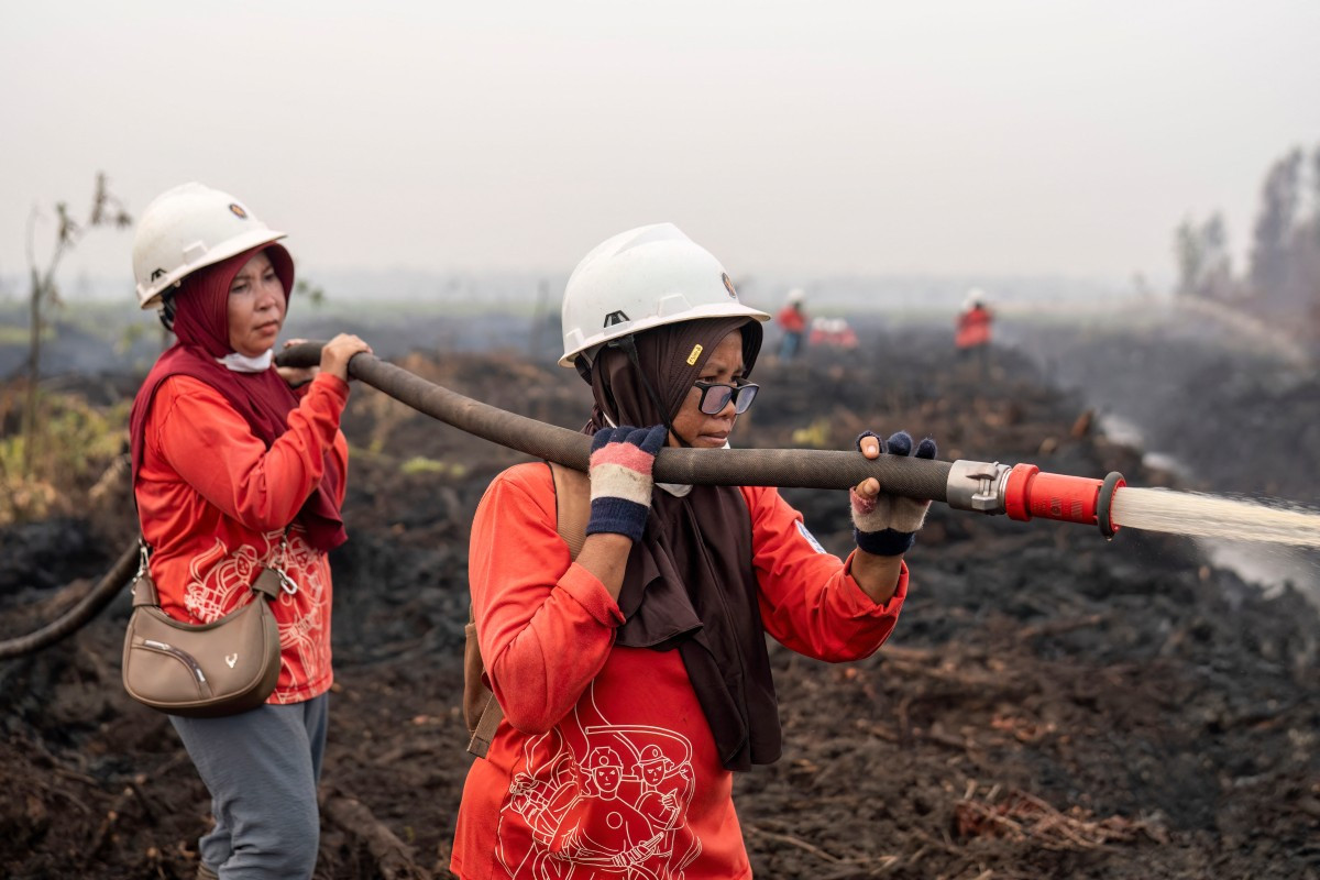 Members of the all-women The Power of Mama (TPoM) volunteer firefighting team spray water onto smoldering peatland in Mensubuk Lama, Tanjungpura Village, Ketapang regency, West Kalimantan on September 26, 2026. Indonesia has been battling fires for weeks in parts of Borneo and Sumatra, sending suffocating haze across the islands and neighboring Malaysia and Singapore.