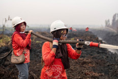 Members of the all-women The Power of Mama (TPoM) volunteer firefighting team spray water onto smoldering peatland in Mensubuk Lama, Tanjungpura Village, Ketapang regency, West Kalimantan on September 26, 2026. Indonesia has been battling fires for weeks in parts of Borneo and Sumatra, sending suffocating haze across the islands and neighboring Malaysia and Singapore.