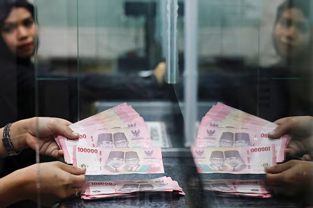 A teller counts rupiah bank notes at a money changer in Jakarta on Jan. 20, 2026. 