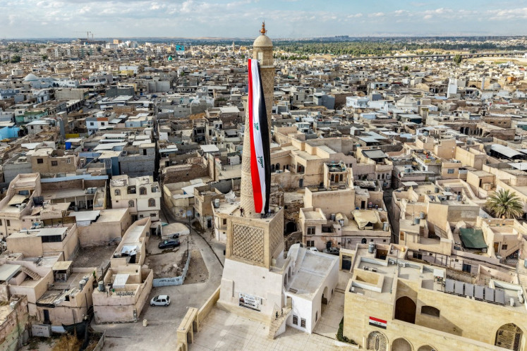 A giant Iraqi flag hangs off the reconstructed 12th century &ldquo;Hadba&ldquo; leaning minaret at the historic Great Mosque of al-Nuri in the old city of Mosul on September 29, 2026 as Iraq marks the withdrawal of the US-led anti-Islamic State coalition forces from the country. After more than a decade, the US-led coalition is ending its mission in Iraq, having helped save the country from jihadists but causing persistent friction in the country. Iraqi Prime Minister Ali al-Zaidi declared that October 1, the day following the coalition's departure, should be celebrated as Sovereignty Day.
