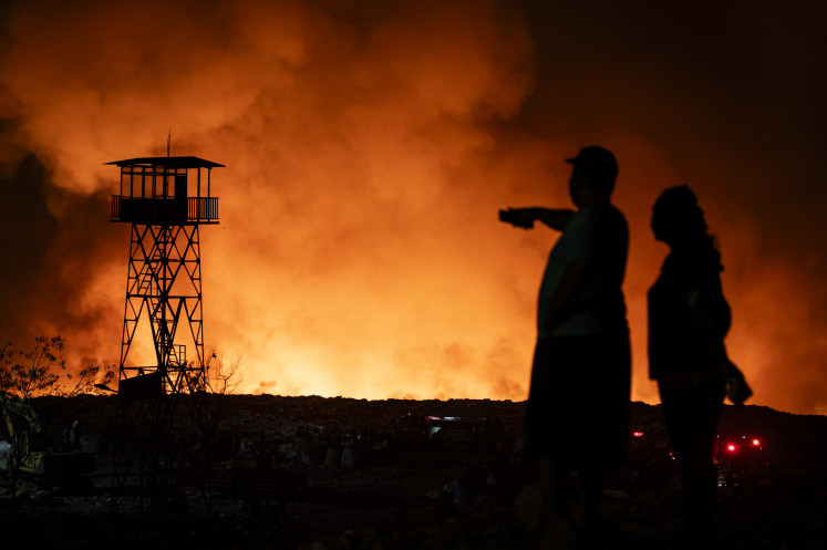 Residents watch on Wednesday as flames engulf piles of garbage at Jatibarang Landfill in Semarang, Central Java. The Semarang Fire and Rescue Agency deployed 50 firefighters and seven fire trucks to tackle the blaze.