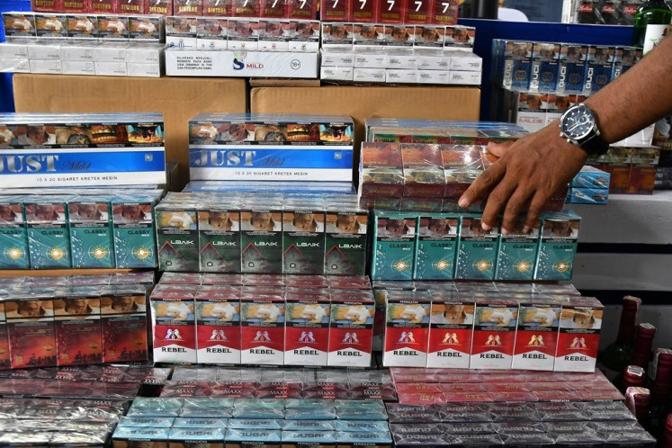 A Bekasi customs and excise official displays confiscated illegal cigarette packages set to be destroyed in Bekasi Regency, West Java on Dec. 6, 2023. 