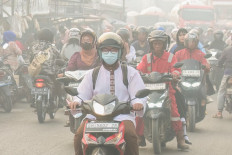 Motorcyclists commute on Oct. 2, 2026, as haze from forest and land fires shroud the road, in Palembang, South Sumatra. Wildfires in Indonesia have been blamed in large part on slash-and-burn land-clearing practices that result in the destruction of fire-resistant forest cover and the draining of peatlands.