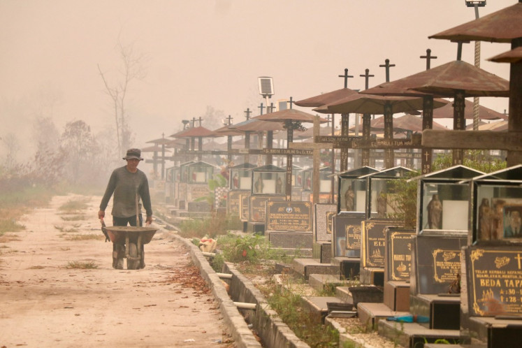 A worker pushes a wheelbarrow through a public cemetery blanketed in thick smoke haze caused by forest and land fires in Palangka Raya, Central Kalimantan on Sept. 30, 2026. Indonesia has experienced major wildfires, while the warming El Nino weather pattern, which started in June and is due to peak later this year, could drive more fires in southeast Asia. 