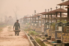 A worker pushes a wheelbarrow through a public cemetery blanketed in thick smoke haze caused by forest and land fires in Palangka Raya, Central Kalimantan on Sept. 30, 2026. Indonesia has experienced major wildfires, while the warming El Nino weather pattern, which started in June and is due to peak later this year, could drive more fires in southeast Asia. 