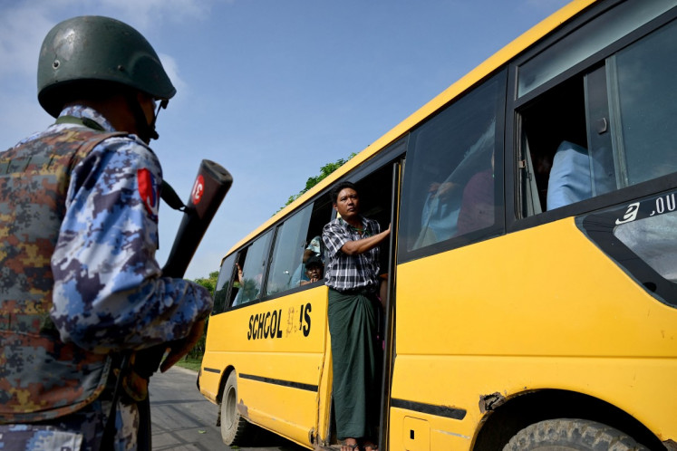 Migrants returning from Malaysia look out from a bus upon their arrival at the Myanmar Navy base in Thanlyin on October 4, 2026. Nearly 1,500 Myanmar migrants from Malaysia arrived in their war-torn home country on October 4, a Myanmar official said, returned under an opaque repatriation scheme that rights monitors say cannot assure their safety.