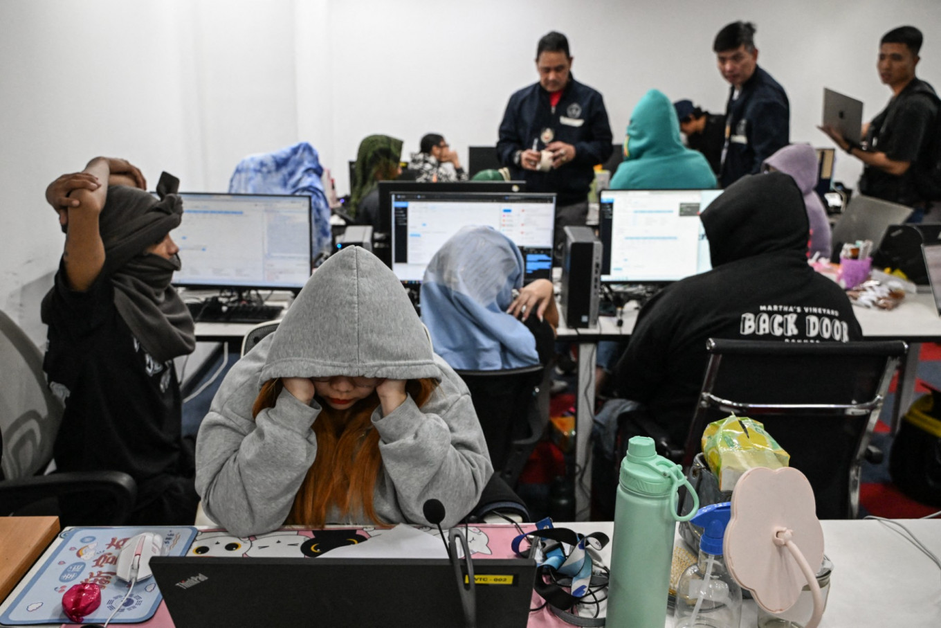 In this file photo, workers sit at their desks during a raid by agents of the Presidential Anti-Organized Crime Commission (PAOCC) and the National Bureau of Investigation at an office of a suspected online scam farm in Manila on January 31, 2025.