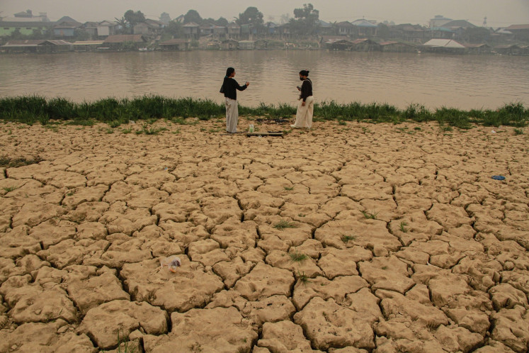 Two women stand on the receded bank of the Kahayan River on Sept. 15 in Palangka Raya, Central Kalimantan.