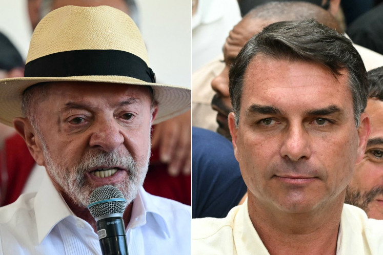 This combination of pictures created on October 4, 2026, shows Brazil's President and re-election candidate for the Workers' Party (PT) Luiz Inacio Lula da Silva (right) speaks to the media after casting his vote during the presidential election at a polling station in Sao Bernardo do Campo, state of Sao Paulo, Brazil, on October 4, 2026; and Brazil's right-wing senator and presidential candidate for the Liberal Party (PL) Flavio Bolsonaro gives thumbs up in front of Rio de Janeiro gubernatorial candidate Douglas Ruas (C, back), as he leaves a polling station after voting during the presidential election in Rio de Janeiro, Brazil, on October 4, 2026. 