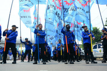 Workers hold flags on Tuesday during a rally outside the House of Representatives (DPR) building on Jl. Gatot Subroto in Central Jakarta calling for the passage of the Employment Protection Bill.