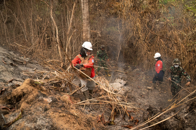 Members of the all-women The Power of Mama (TPoM) volunteer firefighting team and soldiers work on Sept. 27 in a peatland fire area near Tanjungpura village, Ketapang regency, West Kalimantan. Indonesia has been battling fires for weeks in parts of Kalimantan and Sumatra, sending suffocating haze across the islands and neighboring Malaysia and Singapore.