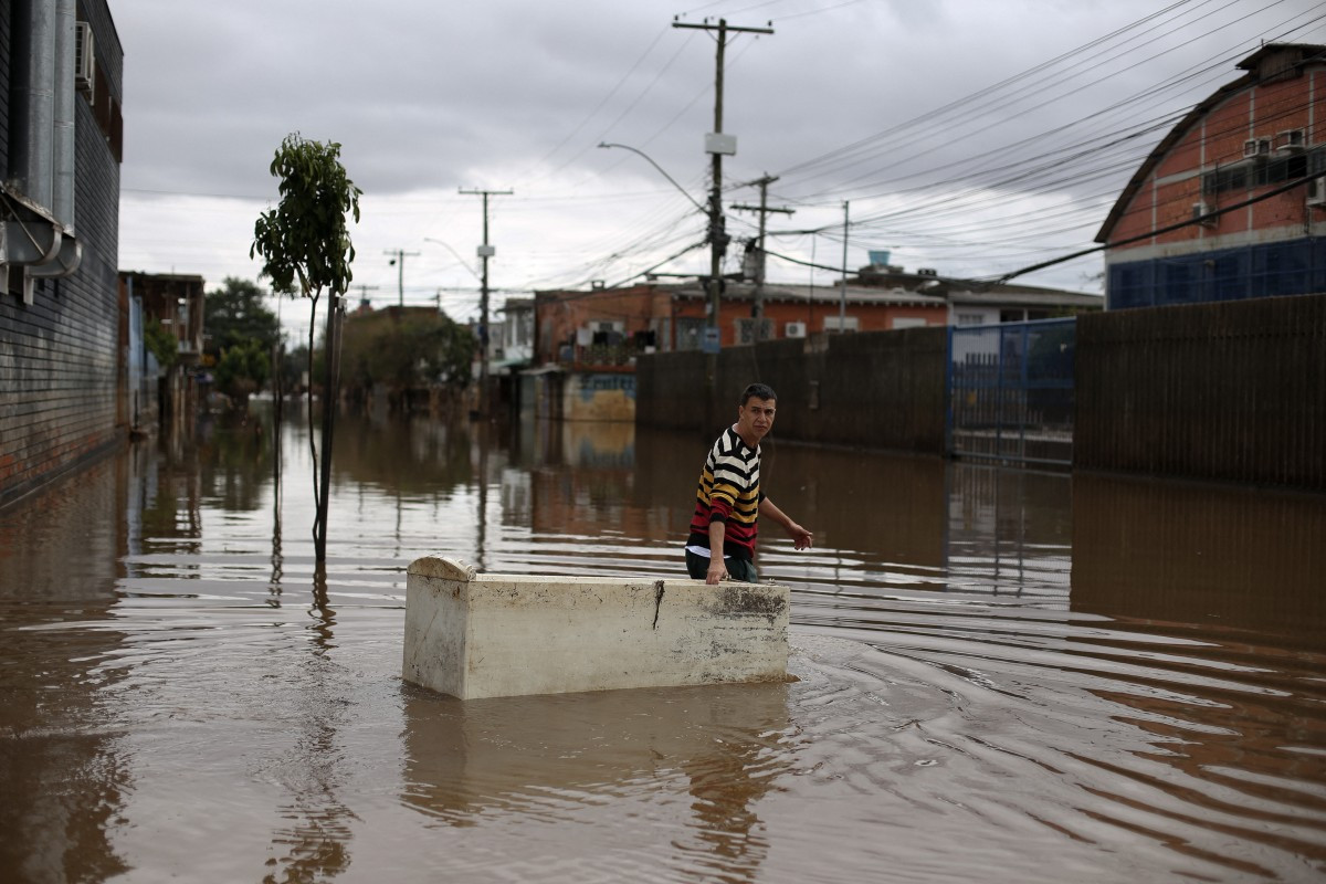 Sander Diego uses a damaged refrigerator as a boat to carry groceries on a flooded street in Porto Alegre, Rio Grande do Sul, Brazil on May 26, 2024. Brazilian prosecutors on October 9, 2026, filed an unprecedented lawsuit against oil giant Shell's subsidiary in the country, demanding US$108 million in compensation over deadly 2024 floods.