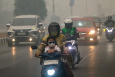 A child and mother wearing face masks ride a motorcycle on Saturday through thick haze from forest and land fires in the region in Palangka Raya, Central Kalimantan. Toxic haze has shrouded parts of Indonesia, Malaysia and Singapore for weeks as Jakarta struggles to contain fires that have scorched large tracts of Kalimantan and Sumatra, with the smoke drifting across the region.