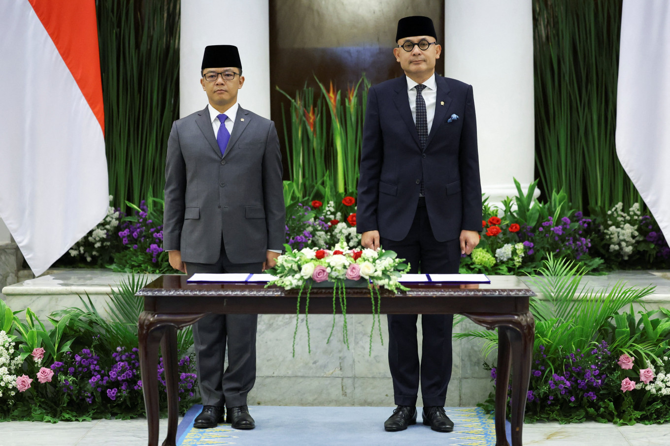 Indonesia's newly appointed Foreign Minister Arrmanatha Nasir (right), and former Foreign Minister and current Coordinating Minister for Human Development and Cultural Affairs, Sugiono, sing the national anthem during a handover ceremony on Oct. 12 in Jakarta.