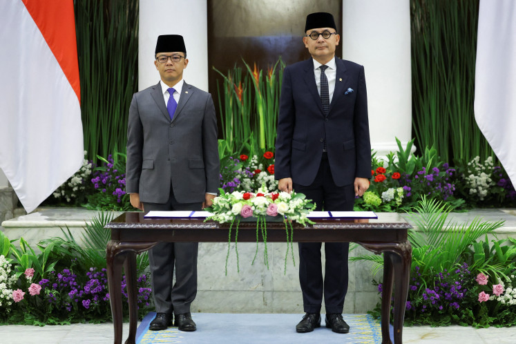 Indonesia's newly appointed Foreign Minister Arrmanatha Nasir (right), and former Foreign Minister and current Coordinating Minister for Human Development and Cultural Affairs, Sugiono, sing the national anthem during a handover ceremony on Oct. 12 in Jakarta.