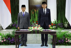 Indonesia's newly appointed Foreign Minister Arrmanatha Nasir (right), and former Foreign Minister and current Coordinating Minister for Human Development and Cultural Affairs, Sugiono, sing the national anthem during a handover ceremony on Oct. 12 in Jakarta.