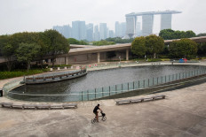 A man rides a bicycle past the Marina Barrage fountain in Singapore on Oct. 6, 2026, just three days before the Formula One Grand Prix, when the air quality in four of the island state&rsquo;s five regions was unhealthy due to transboundary haze from Indonesia.