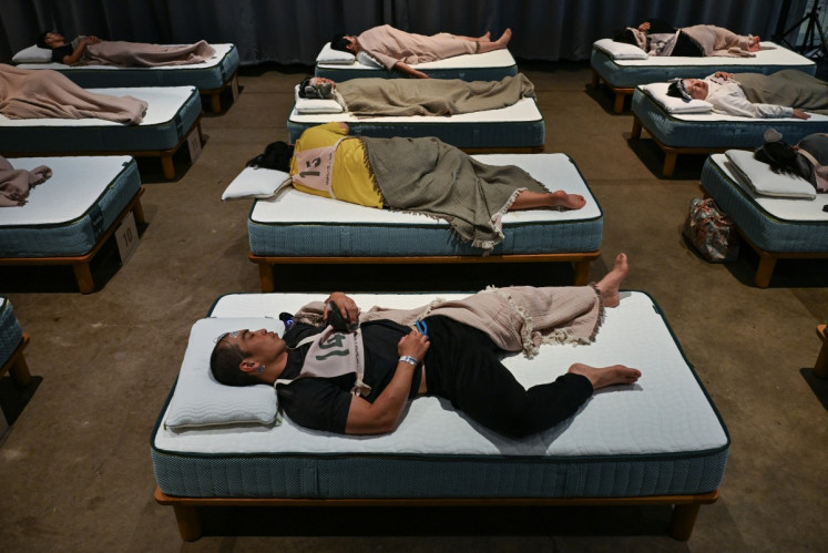 Attendees take part in a sleep competition organized by a mattress brand in Tokyo on October 5, 2026. 