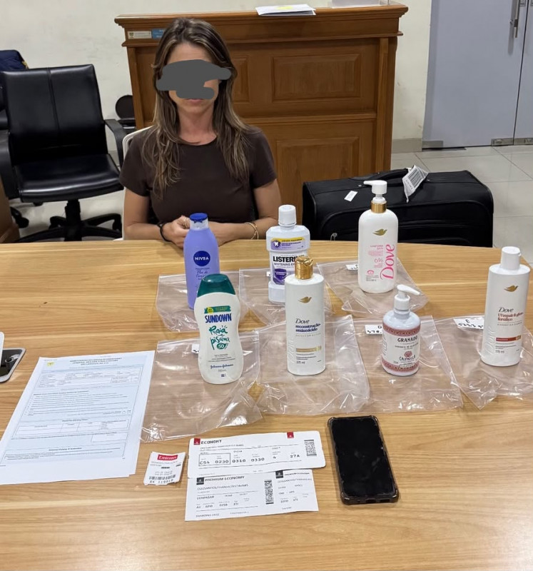 A Brazilian woman, identified only as TCDS, sits in front of seven bottles of personal care products containing some 3.6 kilograms of liquid cocaine after she was arrested upon arrival on Oct. 6, 2026 at the I Gusti Ngurah Rai International Airport in Badung regency, Bali. The suspect said the smuggling attempt was ordered by a man identified only as G, who bore all the cost and promised a fee of US$50,000.