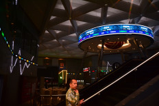 A man uses his mobile phone in front of a reflection of an electronic board displaying stock prices on Oct. 14 at the Indonesia Stock Exchange (IDX) building in South Jakarta.