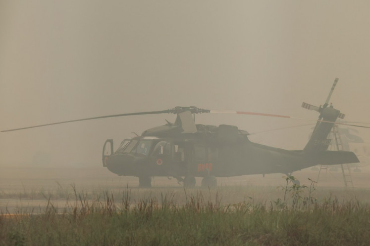 A Sikorsky UH-60 Black Hawk firefighting helicopter operated by the National Disaster Management Agency (BNPB) sits on the tarmac enveloped in haze on Sept. 24 at Tjilik Riwut Airport in Palangka Raya, Central Kalimantan. Low visibility caused by persistent forest fires has hampered both commercial air travel and aerial firefighting operations across the province.