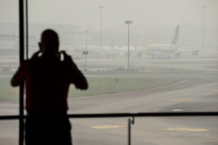 A man takes photographs of airplanes parked on the tarmac at Changi Airport in Singapore on October 16, 2026, as the country continues to be shrouded in haze caused by fires in Indonesia. Toxic haze has covered parts of Indonesia, Malaysia and Singapore for weeks as Jakarta struggles to contain fires that have scorched large tracts of Borneo and Sumatra, with the smoke drifting across the region.
