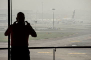 A man takes photographs of airplanes parked on the tarmac at Changi Airport in Singapore on October 16, 2026, as the country continues to be shrouded in haze caused by fires in Indonesia. Toxic haze has covered parts of Indonesia, Malaysia and Singapore for weeks as Jakarta struggles to contain fires that have scorched large tracts of Borneo and Sumatra, with the smoke drifting across the region.
